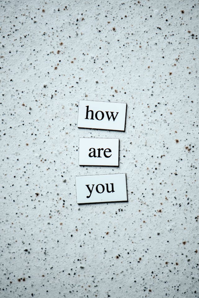 the three words 'how are you' in the form of fridge magnets against a neutral background