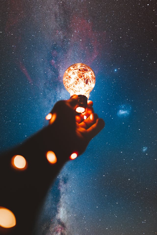 A hand holding a sparkly lightbulb