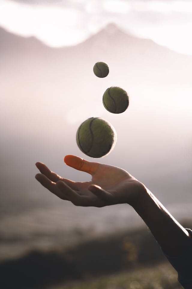 A hand juggling three balls against a misty mountain backdrop